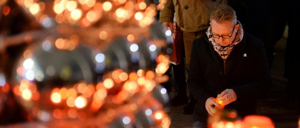 Eine Stadt trauert. Ein Mann kniet am Dienstag nahe der Gedächtniskirche vor Kerzen und Blumen. 