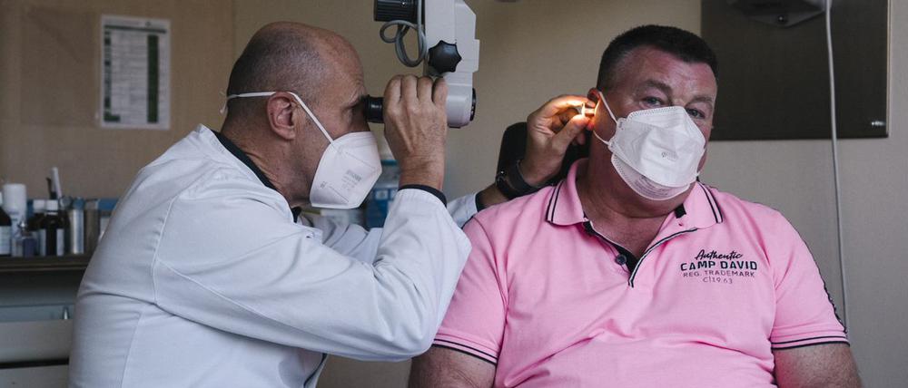 Chefarzt Marc Bloching kontrolliert das Ohr seines Patienten Heiko Dörge