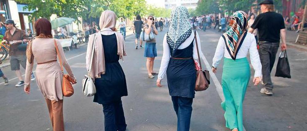 Junge Frauen, die Kopftücher tragen, gehen eine Straße herunter.