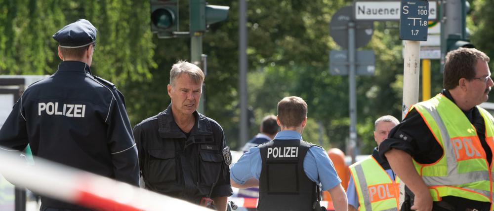Polizisten stehen in Spandau an der Kreuzung Nauener Straße/Brunsbütteler Damm.