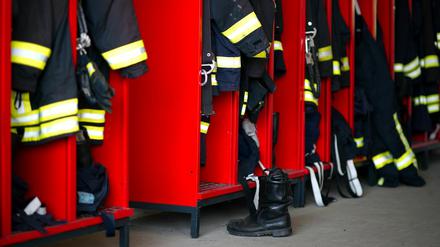 Firefighter clothing hangs in several lockers.
