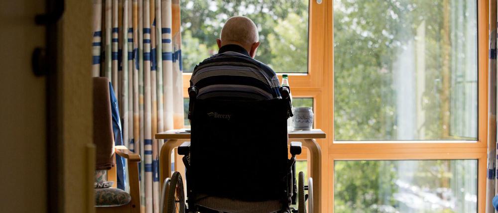 Ein an den Rollstuhl gebundener Bewohner sitzt in einem Altenpflegeheim in seinem Zimmer.