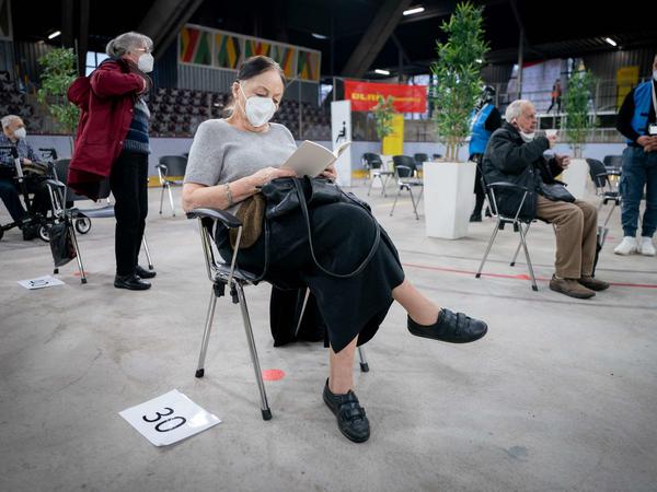 Eine Frau ruht sich nach ihrer Impfung im Erika-Heß-Eisstadion kurz aus.