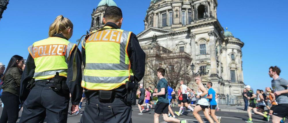 Zwei Polizisten stehen an der Halbmarathonstrecke in Berlin vor dem Dom.