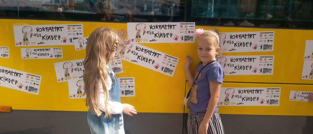 Marlene und Emilia kleben die "Vorfahrt für Kinder"-Sticker auf einen BVG-Bus. Am Sonnabend werden die Mädchen eingeschult.