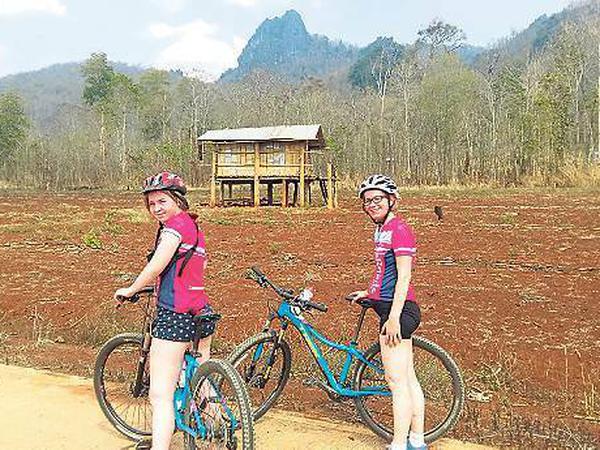 Unsere Autorin (rechts) hat mit ihrer Tochter und dem pinkfarbenen Radlerdress ihren großen Auftritt in thailändischen Dörfern. 