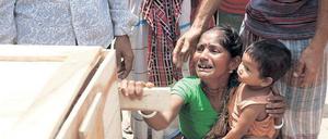 Hinterbliebene. Eine Frau weint um ihre getötete Schwester. Auf dem Schoß hat sie die Tochter der Toten. Viele der Arbeiterinnen in der eingestürzten Fabrik in Bangladesch waren alleinerziehende Mütter. Was aus den Waisen wird, ist unklar. Foto: Abir Abdullah/dpa