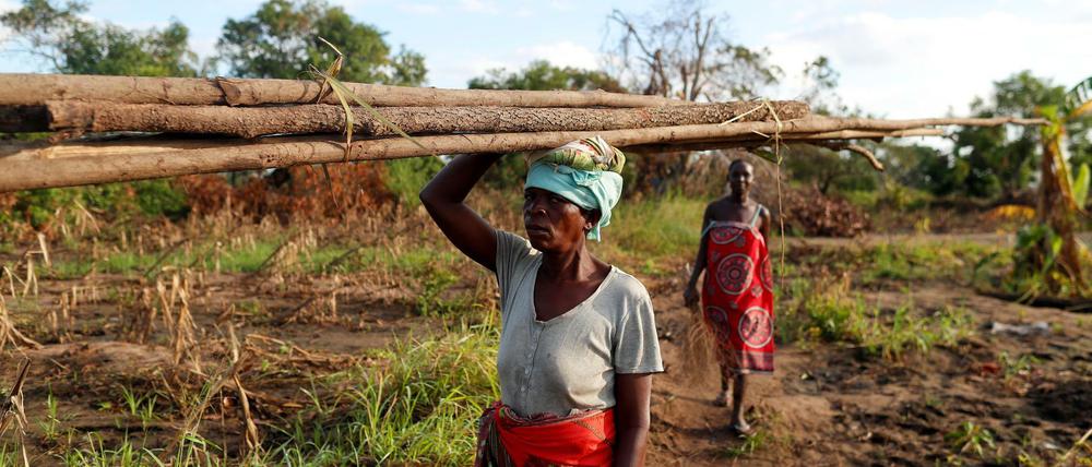 Eine Frau trägt Holz zur Wiedererrichtung einer Hütte in der Nähe von Beira in Mosambik.