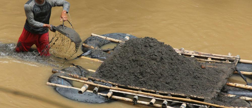Ein Arbeiter schüttet Sand vom Grund des Pepe-Flusses in Bolon (Karanganyar, Indonesien) auf ein Floß. Indonesien verliert durch Sandexporte immer mehr Teile seines Territoriums