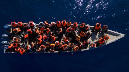 Migranten aus Eritrea, Libyen und dem Sudan sitzen in einem Holzboot auf dem Mittelmeer (Archivbild).