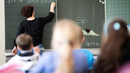 Eine Lehrerin schreibt in einer Grundschule Wörter an eine Tafel. 