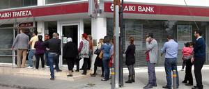 Menschen stehen Schlange, um Cash aus dem Geldautomat einer geschlossenen Bank in Nikosia zu bekommen.
