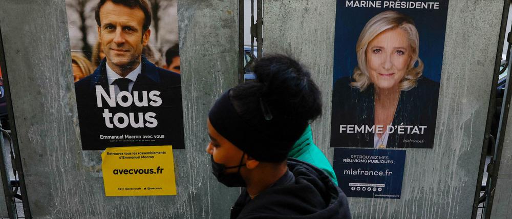 Ein Mann geht an Wahlplakaten des französischen Präsidenten Macron und der Präsidentschaftskandidatin der rechtsextremen Partei Rassemblement National (RN), Le Pen, im Südwesten Frankreichs vorbei. Die Präsidentschaftswahlen werden in zwei Runden am 10. und 24. April 2022 stattfinden.