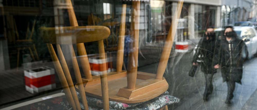Hochgestellte Stühle sind durch die Scheibe eines Cafés in der Kneipenmeile von Halle/Saale. 