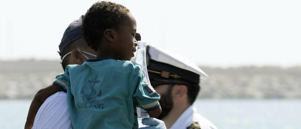 Ein Sanitäter hält ein Kind, nachdem dieses von Bord eines Schiffes der italienischen Küstenwache ging. 
