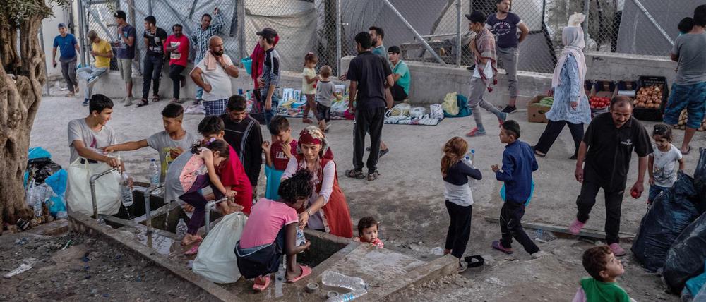 Menschen stehen um eine Wasserstelle und befüllen Flaschen im Flüchtlingslager Moria auf der griechischen Insel Lesbos. 