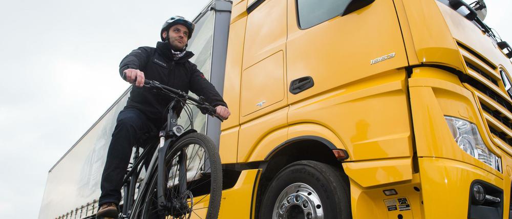 Ein Radfahrer steht mit seinem Fahrrad neben einem LKW mit einem Abbiegeassistenten.