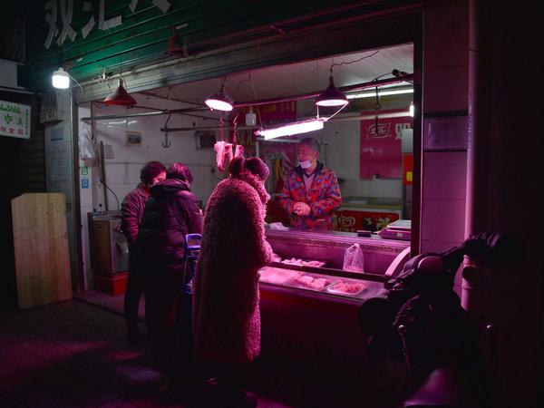 Ein Fleischverkäufer mit Kunden in Wuhan. In China steht das Neujahrsfest bevor, normalerwiese sind Märkte vor dem Ereignis überfüllt.
