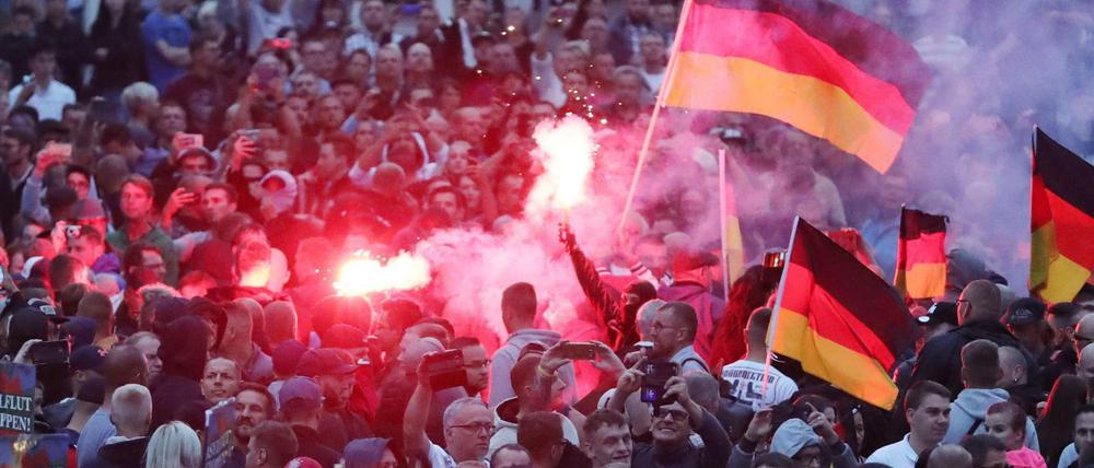 Demonstranten der rechten Szene zünden am 27. August 2018 in Chemnitz Pyrotechnik und schwenken Deutschlandfahnen. Nach einem Streit war in der Nacht zu Sonntag in der Innenstadt von Chemnitz ein 35-jähriger Mann erstochen worden. Die Tat war Anlass für spontane Demonstrationen, bei denen es auch zu Jagdszenen und Gewaltausbrüchen kam.
