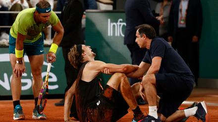 Alexander Zverev kann aus eigener Kraft nicht mehr aufstehen, Rafael Nadal bietet seine Hilfe an.