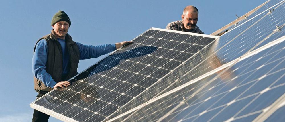 Zwei Arbeiter bei der Montage einer Photovoltaik-Anlage auf einem Hausdach. Das könnte bei Neubauten bald Pflicht sein. 