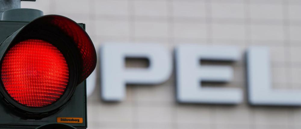 Eine rote Ampel leuchtet vor dem Opel-Schriftzug in Rüsselsheim.