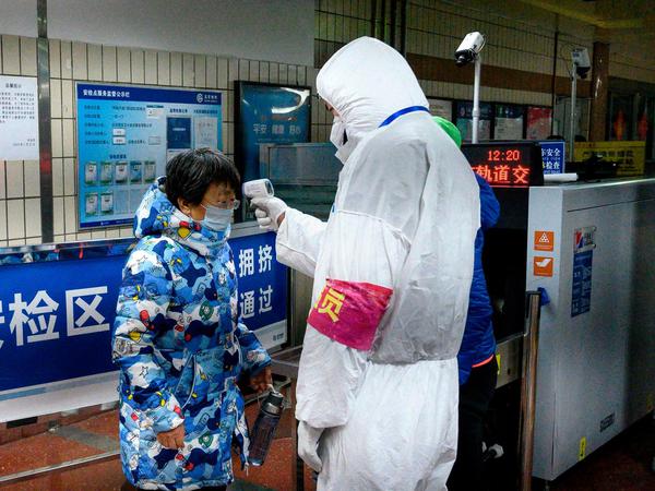 Ein Sicherheitsmitarbeiter misst die Temperatur bei einer Frau in der U-Bahn in Peking.