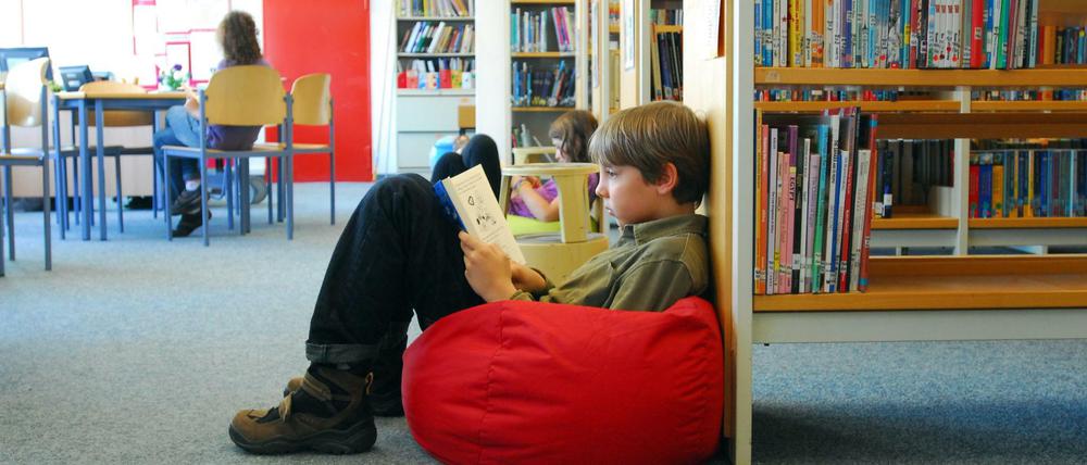 Kinder sitzen in einer Bibliothek auf Sitzsäcken und lesen.