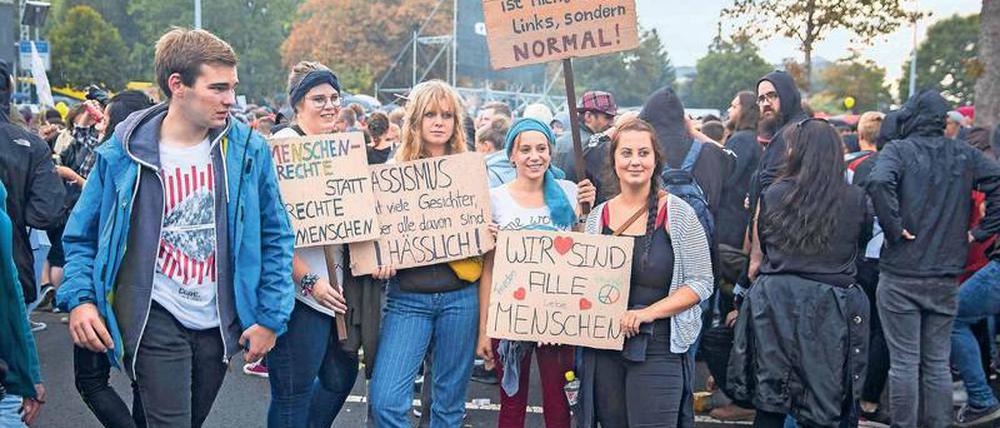Eine Gruppe junger Menschen hält bei einer Demonstration in Chemnitz Plakate mit Aufschriften wie "Wir sind alle Menschen" und "Menschenrechte statt rechte Menschen" hoch.
