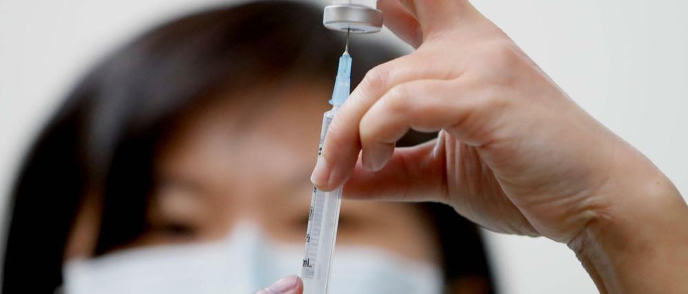 Eine Krankenschwester zieht Impfstoff in eine Spritze.